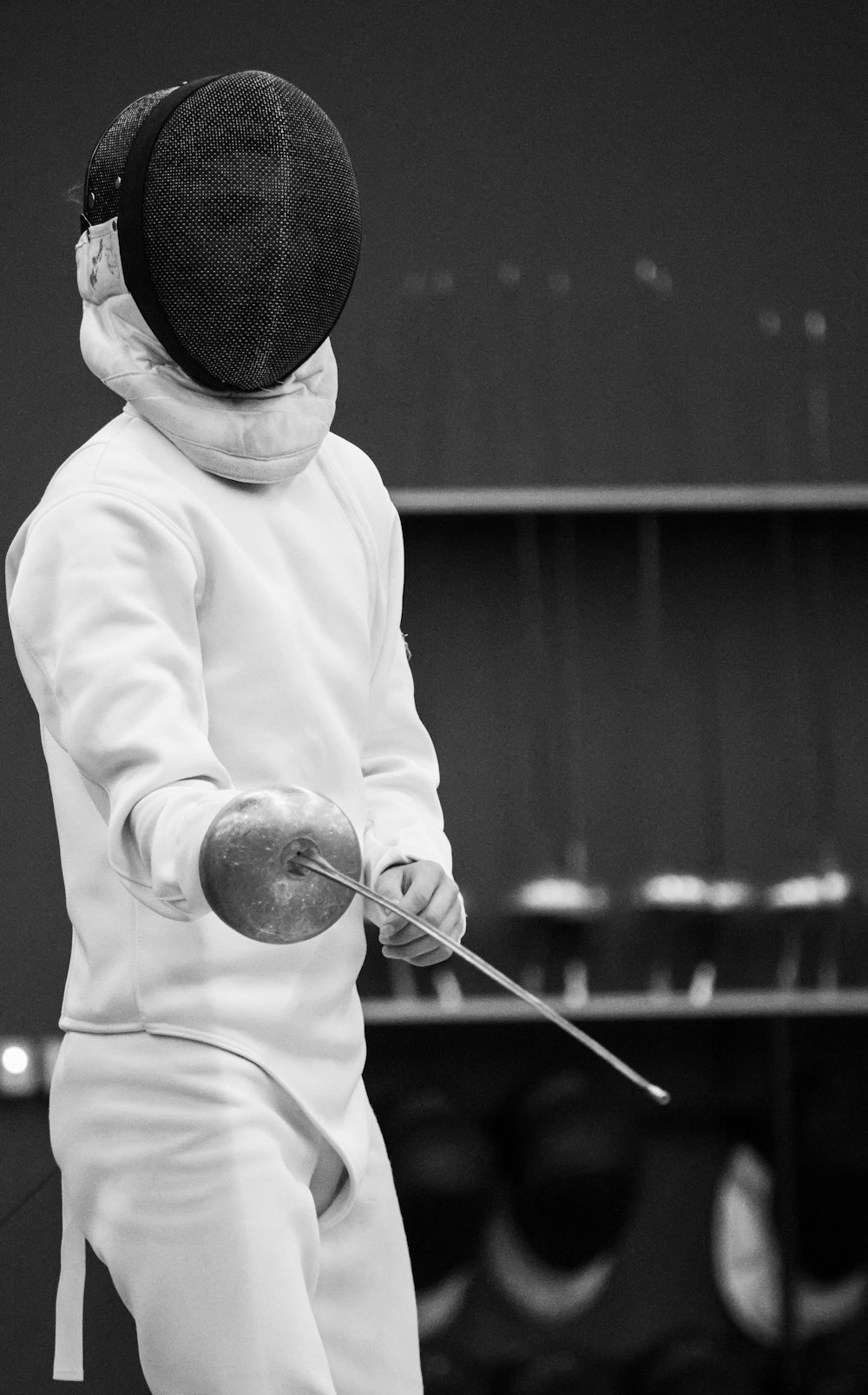 Épée fencer in mask and white kit standing on guard