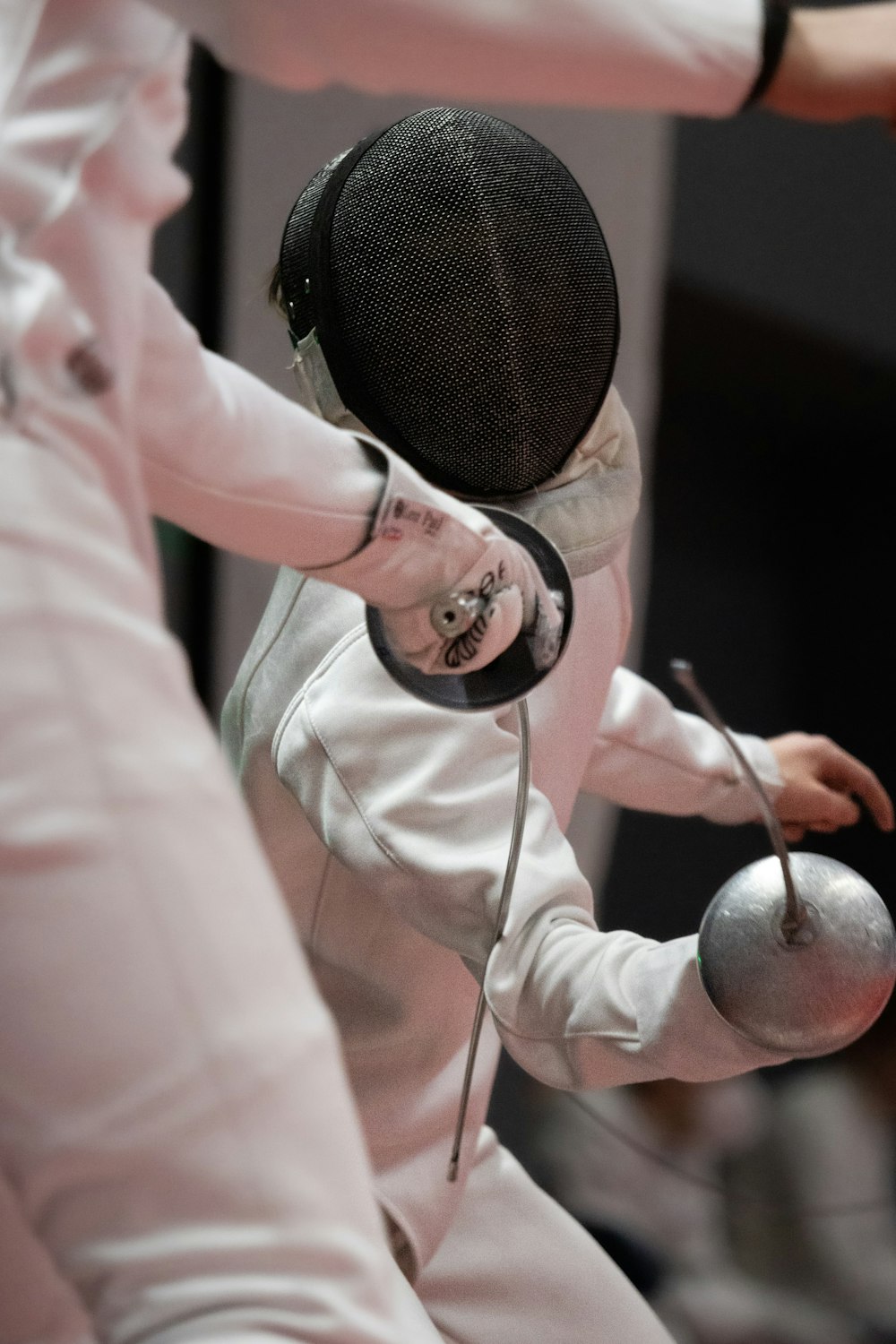 Close-up of two épée fencers at close quarters, showing a mask and the bell guards of their weapons